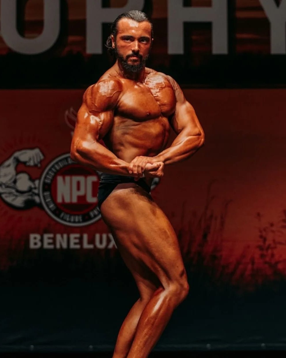 Max Moens poseert op het podium van een NPC Benelux bodybuildingwedstrijd